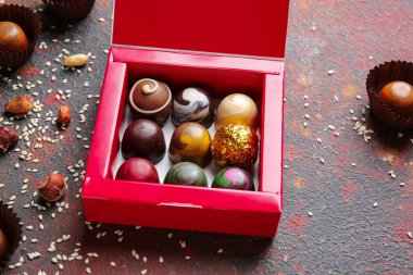 Arkaplanda lezzetli çikolata şekerleri olan bir kutu.