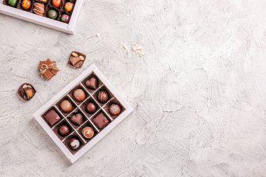 Hafif arka planda lezzetli çikolata şekerleriyle dolu bir kutu.