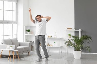 Yakışıklı delikanlı dans ediyor ve evde müzik dinliyor.