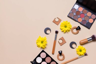 Gri arka planda küpeleri olan makyaj malzemeleri.