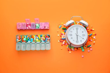 Farklı haplar ve renk arkaplan üzerindeki saat kompozisyonu