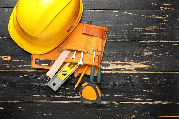 Builder's tools and hardhat on wooden background