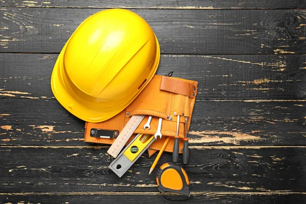 Builder's tools and hardhat on wooden background