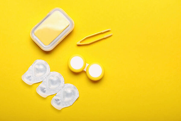 Контейнеры для контактных линз и пинцета на цветном фоне
