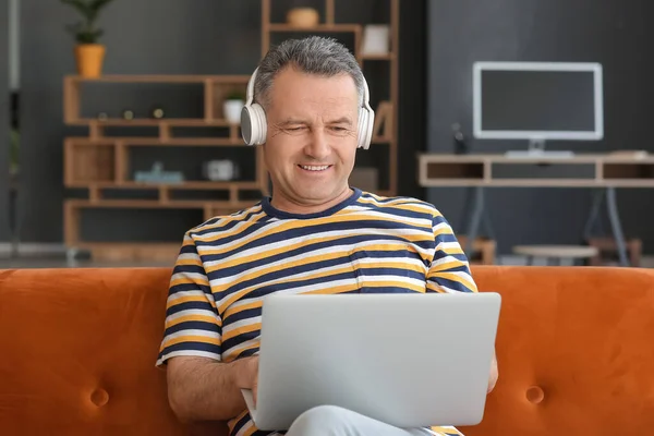 Volwassen Man Met Laptop Hoofdtelefoon Zittend Bank Thuis — Stockfoto