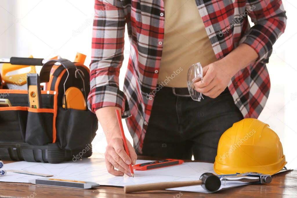 Male builder working with house plan in office