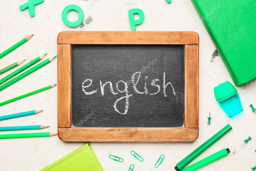 Chalkboard with text ENGLISH and stationery on white background