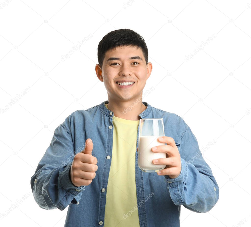 Young Asian man with milk showing thumb-up on white background