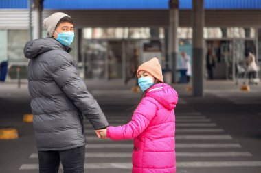 Şehir caddesinde koruyucu maskeler takan Asyalı bir aile. Salgın kavramı