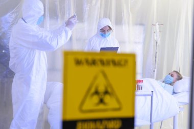Biyolojik tehlike giysileri içindeki doktorlar bulaşıcı izolasyon koğuşundaki hastalarla çalışıyorlar. Coronavirüs salgını kavramı