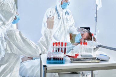 Biyolojik tehlike giysileri içindeki doktorlar bulaşıcı izolasyon koğuşundaki hastalarla çalışıyorlar. Coronavirüs salgını kavramı