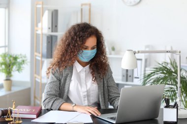 Koruyucu maskeli kadın avukat ofiste çalışıyor.
