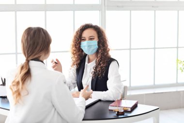 Koruyucu maskeli kadın avukat ofiste müşteriyle çalışıyor.