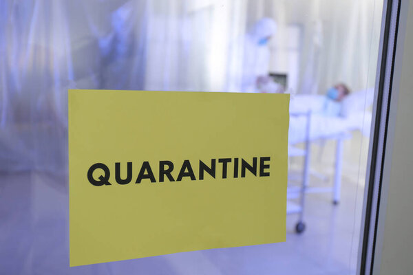 Бумажный лист с текстом QUARANTINE на двери заразной изоляционной палаты
