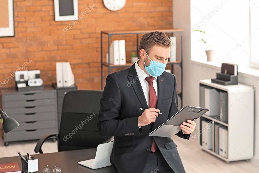 Male lawyer in protective mask working in office