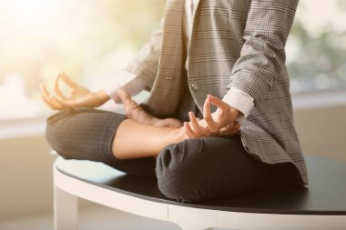Genç iş kadını ofiste meditasyon yapıyor.