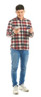 Beyaz arka planda kredi kartı ve cep telefonu olan Asyalı bir adam.