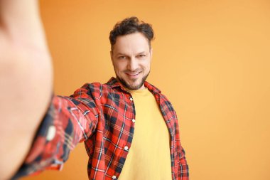 Renkli arka planda selfie çeken şık bir adam.