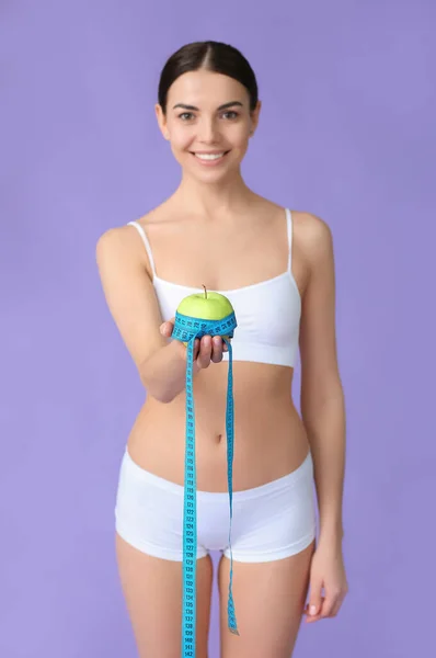 色の背景にテープやリンゴを測定する若い女性 減量の概念 — ストック写真
