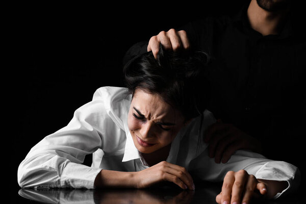 Angry husband trying to kill his wife on dark background. Concept of domestic violence