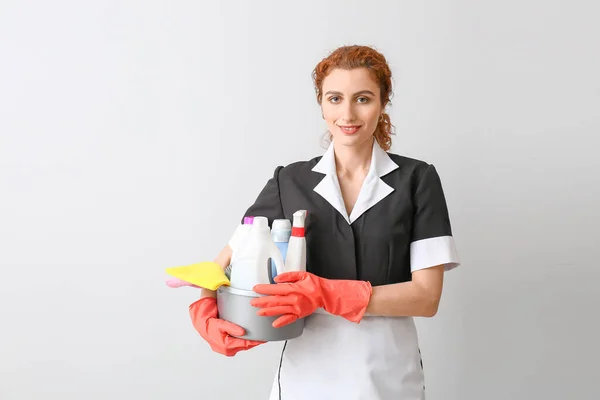 Beautiful Young Chambermaid Cleaning Supplies Light Background — Stock Photo, Image