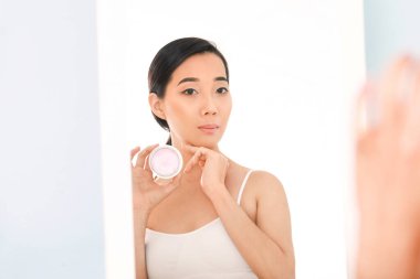 Güzel genç Asyalı kadın evde krem sürüyor.