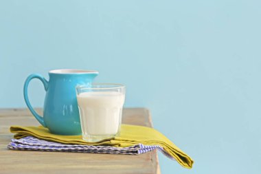 Masanın üzerinde renk arkaplanına karşı bir bardak süt.