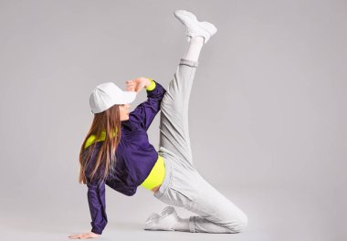 Gri arka planda genç bayan hip-hop dansçısı