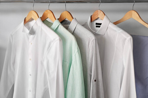 Stylish male clothes on hanger in wardrobe
