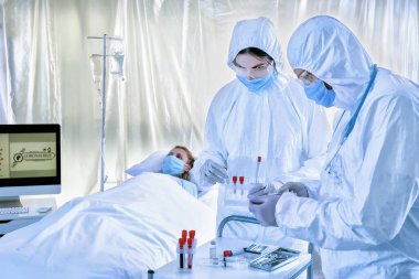Biyolojik tehlike giysileri içindeki doktorlar bulaşıcı izolasyon koğuşundaki hastalarla çalışıyorlar. Coronavirüs salgını kavramı