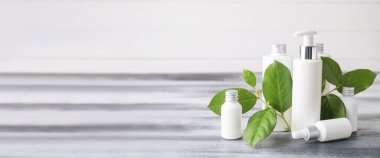 Ahşap masadaki şişelerde farklı kozmetik ürünleri ve metin için yer var.