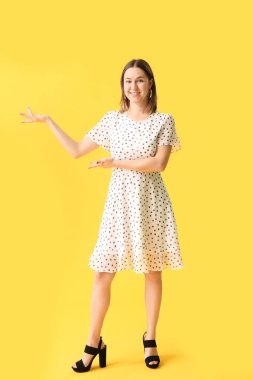 Güzel genç bir kadın, arka planda bir şeyler gösteriyor.