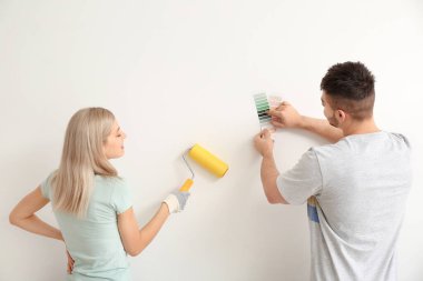 Genç çift beyaz arkaplanda duvar rengini seçiyor