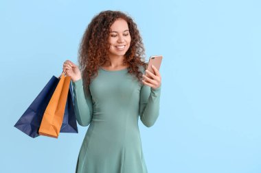 Cep telefonu ve renkli çantaları olan genç bir kadın.