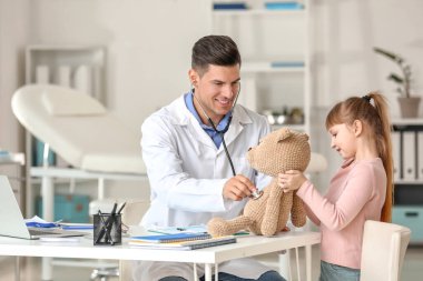 Küçük kız nasıl klinikte stetoskop kullanılacağını gösteren oyuncak çocuk doktoru