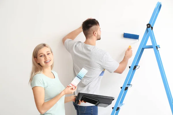 Genç Çift Beyaz Arkaplanda Duvar Rengini Seçiyor — Stok fotoğraf