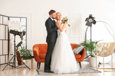 Genç bir çift stüdyoda fotoğrafçıya poz veriyor.