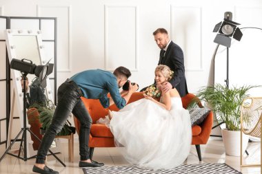 Photographer working with young wedding couple in studio