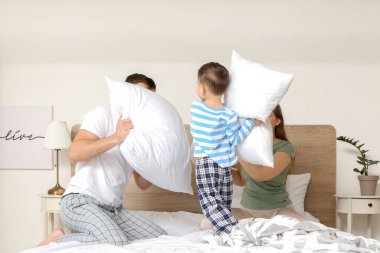 Yatak odasında mutlu bir aile arasında yastık savaşı