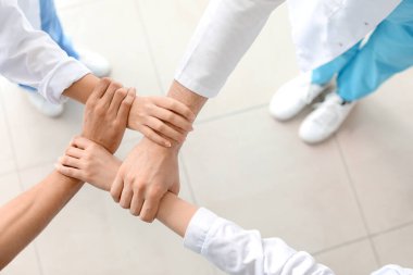 Klinikte el ele tutuşan bir grup doktor. Birlik kavramı