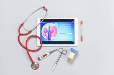 Steteskoplu tablet bilgisayar ve gri arka planda idrar örneği.