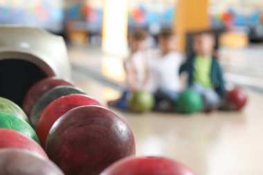 Bowling kulübünde toplarla dikil ve arka planda bulanık çocuklar olsun.