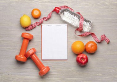 Sağlıklı ürünler, mezuralar ve halterlerle dolu bir defter.