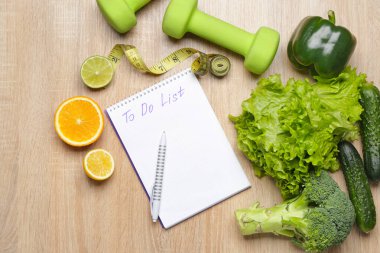 Sağlıklı ürünler, yemek planı, mezura ve ahşap arka plandaki dambıllar.