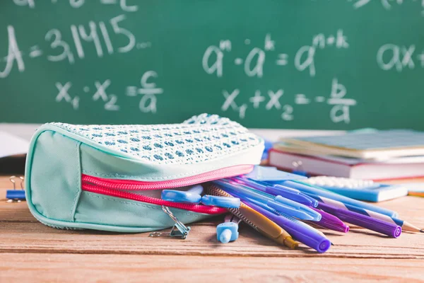 Pencil bag with stationery on desk in classroom