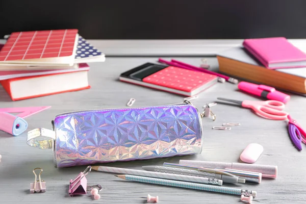 Pencil bag with stationery on desk in classroom