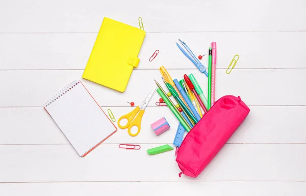 Pencil bag with stationery on wooden background