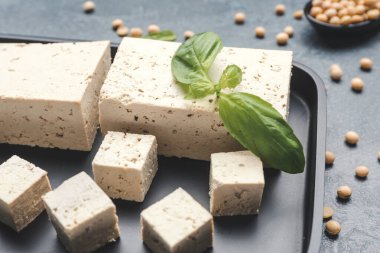 Koyu arkaplanda lezzetli tofu peyniri tabağı, yakın plan.