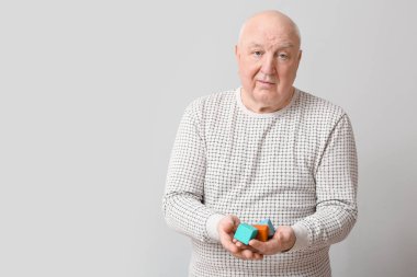 Gri arka planda küpleri olan zihinsel engelli yaşlı bir adam