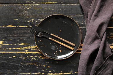 Koyu ahşap arka planda temiz tabak ve çatal bıçak.